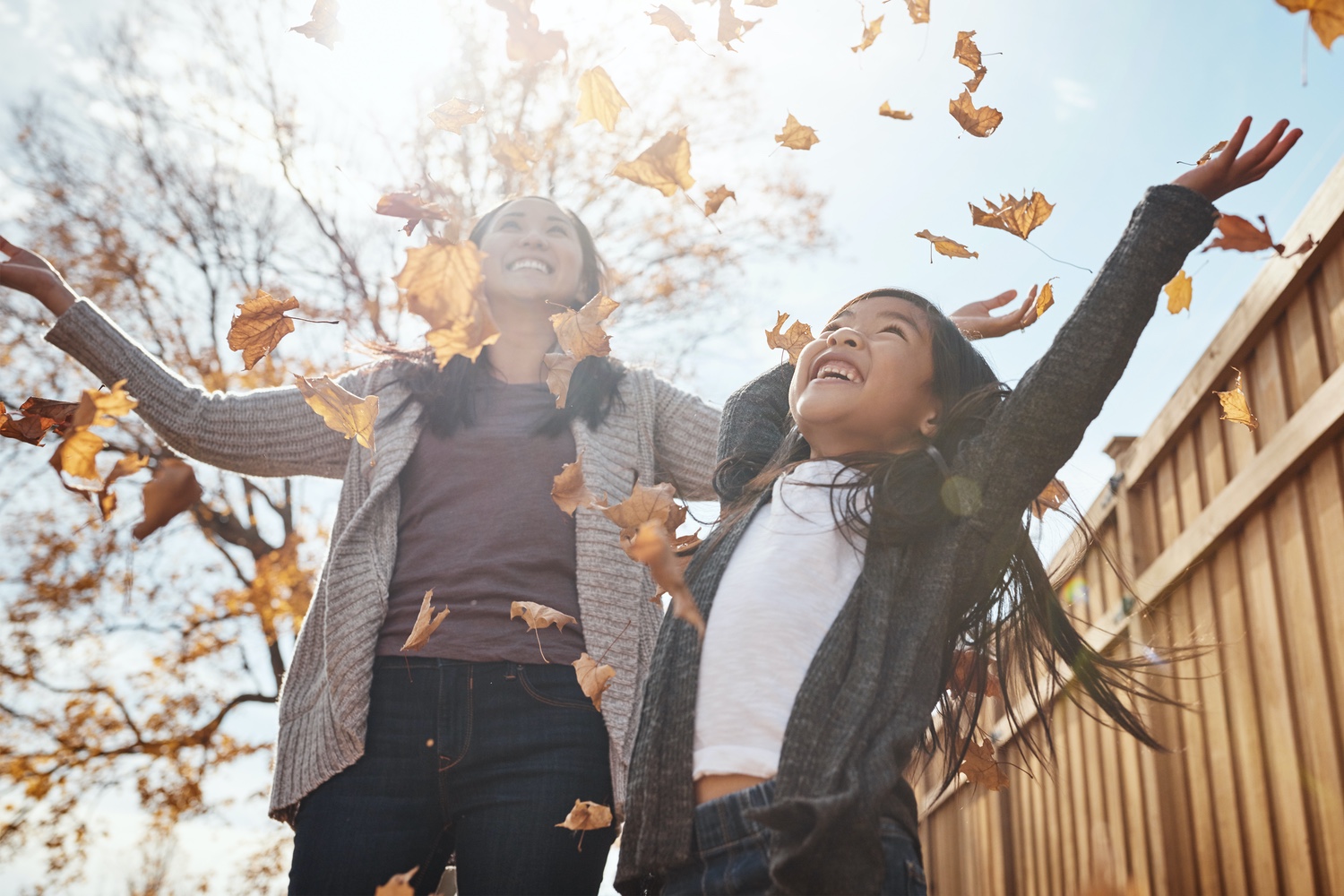 mother and daughter throwing leaves