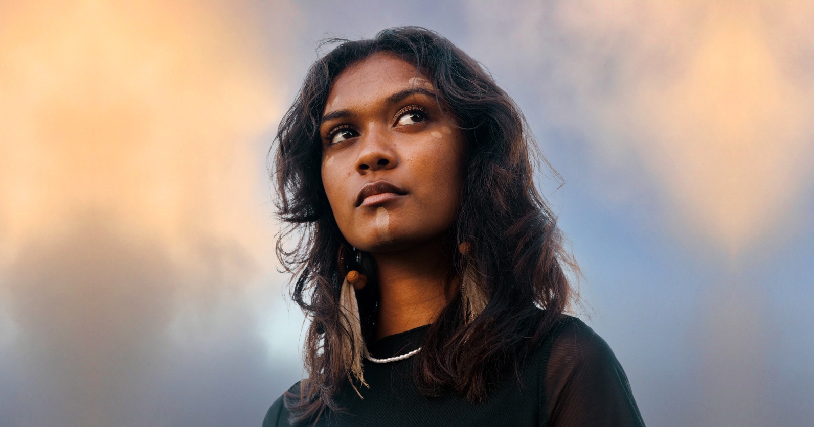 Aboriginal woman in front of a blue and orange sky